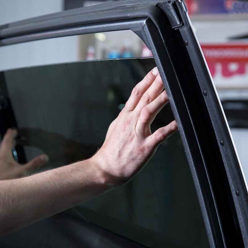 A person reaching to open a car window symbolizes the need for auto glass services in Burnaby, BC.
