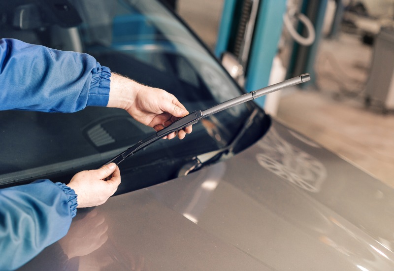 A Man repairs a car windshield in Burnaby, BC, installing a new windshield wiper blade.