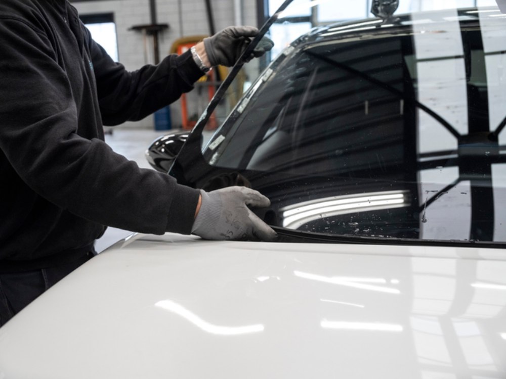 Mechanic performing windshield installation or repair work on vehicle in Burnaby, BC